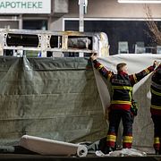 Brandmän täcker över den brandhärjade bussen.