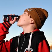 Pojke dricker ur en burk med energidryck.