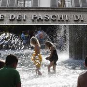 Italienska barn som badar i centrala Milano. Entre till ett Monte dei Paschi-kontor. Arkivbilder.