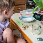 Pojke äter frukost och ser på tecknat på en mobiltelefon. 
