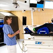 En patient ligger på britsen i en strålningsmaskin och får behandling för en tumör i bålen på en canceravdelning på Karolinska universitetssjukhuset i Solna.
