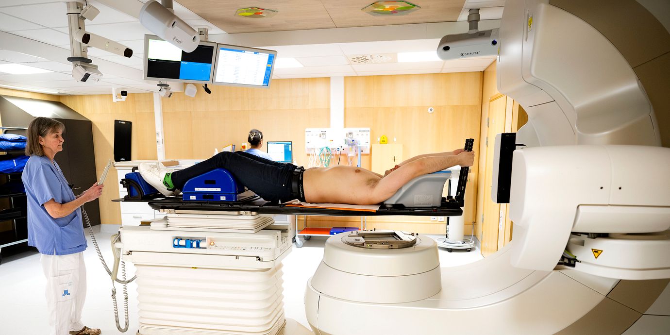 En patient ligger på britsen i en strålningsmaskin och får behandling för en tumör i bålen på en canceravdelning på Karolinska universitetssjukhuset i Solna.