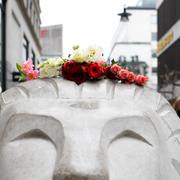 Förbipasserande lägger blommor utanför Åhléns på Drottninggatan på årsdagen för terrordådet den 7 april 2017.