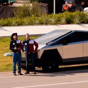 Två män i Texasmönstrade skjortor tittar upp mot Teslas ”Gigafactory” i Austin. 