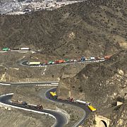 Rök stiger över en bergskam nära gränsen mellan Afghanistan och Pakistan. På vägen syns lastbilar som har blivit stående när vägen stängdes.