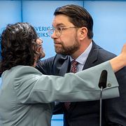 Liberalernas partiledare Simona Mohamsson och Sverigedemokraternas Jimmie Åkesson kramas vid en pressträff den 13 mars 2026.