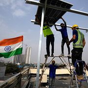 Arbetare placerar en solpanel på taket av ett bostadshus i Gurugram, i utkanten av New Delhi.