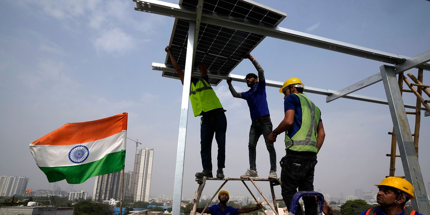 Arbetare placerar en solpanel på taket av ett bostadshus i Gurugram, i utkanten av New Delhi.