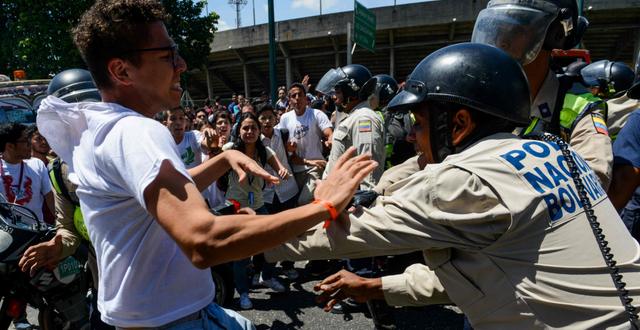 En demonstrant knuffas bort av en polis vid en demonstration i Caracas den 15 februari. FEDERICO PARRA / AFP