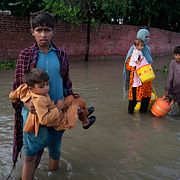 En familj vadar genom vatten efter en översvämning i Pakistan i augusti 2025. Arkivbild.