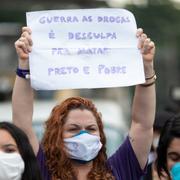 Kvinna i Rio de Janeiro. Skylt med texten: ”Kriget mot drogerna är en ursäkt för att döda svarta och fattiga”. 