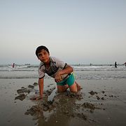 Pojke lekar i strandkanten vid Persiska viken där en stor del av Irankriget har utspelat sig.