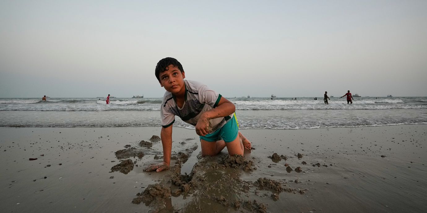 Pojke lekar i strandkanten vid Persiska viken där en stor del av Irankriget har utspelat sig.