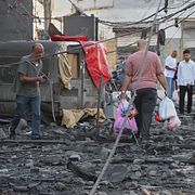 En man bär sina tillhörigheter i plastpåsar efter en israelisk attack mot Tyr.