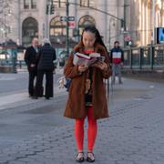 En person läser en bok på ett torg i New York.