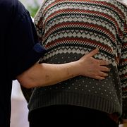 Ett vårdbiträde håller handen på ryggen på en person som bor på ett vårdboende för äldre. Arkivbild.