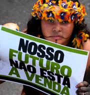 En flicka bär en lapp med testen ”Vår framtid är inte till salu” under demonstrationen i Brasilia. Eraldo Peres / AP