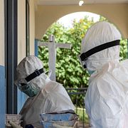 Sjukvårdspersonal i skyddsdräkter bär in mat till Ebolapatienter i Kongo.