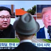 En man tittar på tv-bilder av Kim Jong-Un och Donald Trump. 