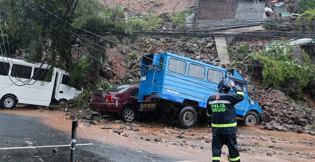 En polisman kontrollerar en bil som har hamnat under ett jordskred orsakad tyfonen i Baguio, norra Filippinerna.  AP