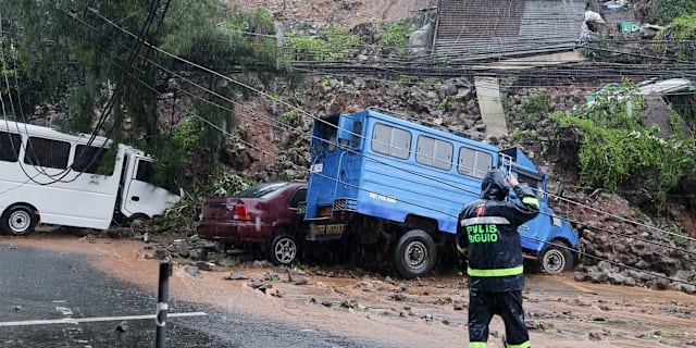 En polisman kontrollerar en bil som har hamnat under ett jordskred orsakad tyfonen i Baguio, norra Filippinerna.  AP