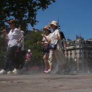 Turister som går genom en vattenspridare i Paris på måndagen. 