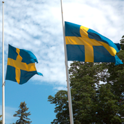 Människor lägger blommor utanför polishuset i Göteborg. Flaggor på halv stång utanför polishuset i Stockholm. 