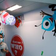 In this Friday, Oct. 23, 2020 photo, an employee walks past the picture of Ant Group's mascot at the Ant Group office in Hong Kong. China's Ant Group will try to raise nearly $35 billion in its initial public offering in Shanghai and Hong Kong, which would make it the largest share offering in history.