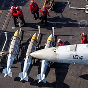 Besättningsmän från den amerikanska flottan lastar vapen på ett F/A-18F Super Hornet ombord på hangarfartyget USS Abraham Lincoln.