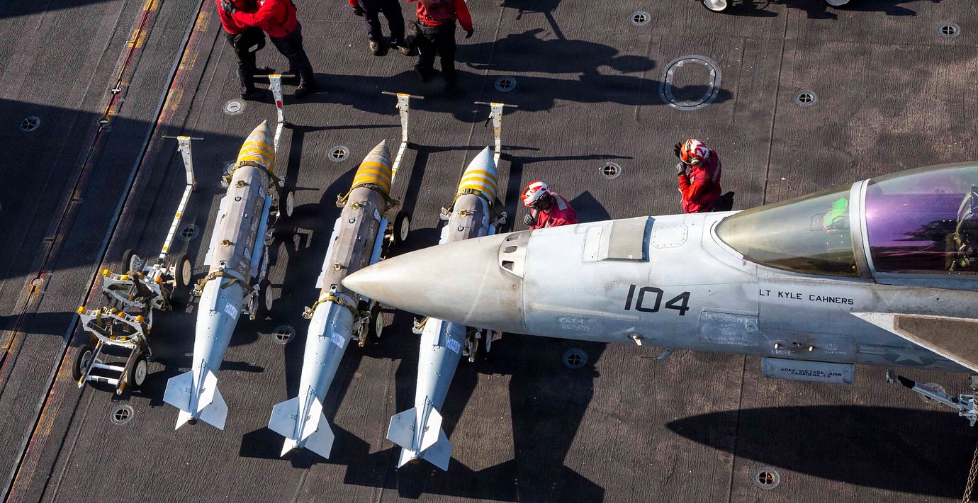 Besättningsmän från den amerikanska flottan lastar vapen på ett F/A-18F Super Hornet ombord på hangarfartyget USS Abraham Lincoln.