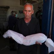 En man bär på ett barn som dödats i en israelisk attack i Gaza. 