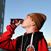 En pojke dricker ur en burk med energidryck. Illustrationsbild. 