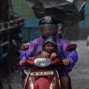 Trafikanter i Mumbai försöker freda sig från regnmassor.