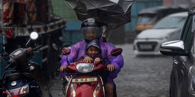 Trafikanter i Mumbai försöker freda sig från regnmassor. Rafiq Maqbool / AP