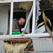 En invånare i Zaporizjzja städar upp på sin balkong efter en rysk attack på onsdagen.