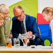 Friedrich Merz utför experiment med barn på en förskola i Potsdam.