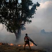 En man släcker en eld i norra Israel efter att Hizbollah avfyrat raketer.