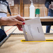 Ett valkuvert med en röst i riksdagsvalet läggs i valurna i en vallokal i Malmö, 2022. 