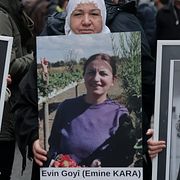 Demonstranter håller upp porträtt av Emine Kara intill bilder på de kurdiska kvinnor som mördades i Paris 2013. 