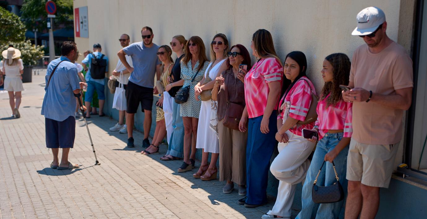Turister som håller sig i skuggan utanför Sagrada Familia i Barcelona. 