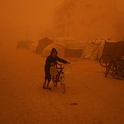 En pojke som knuffar sin cykel genom en sandstorm i ett krigshärjat Khan Younis i Gaza. Illustrationsbild.