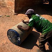 En Lusakabo rullar ett oljefat med vatten genom sitt kvarter i Zambias huvudstad. Bilden är tagen 2024.