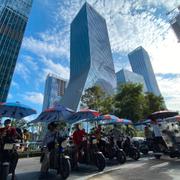 Men on electric bikes wait for riders near the Evergrande headquarters, center, in Shenzhen, China, Friday, Sept. 24, 2021.