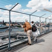 Turister som tittar ut över och fotograferar Slussenbygget från Katarinahissen, juli 2020.