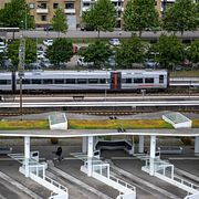 Ett Öresundståg viid perrong och en regionbuss tillhörande Hallandstrafiken på Halmstad Central ( Halmstads Centralstation ) och resecentrum i augusti 2025.  
