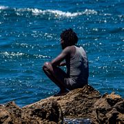 En man som tagit sig från Marocko till Ceuta sitter på stranden på söndagen.