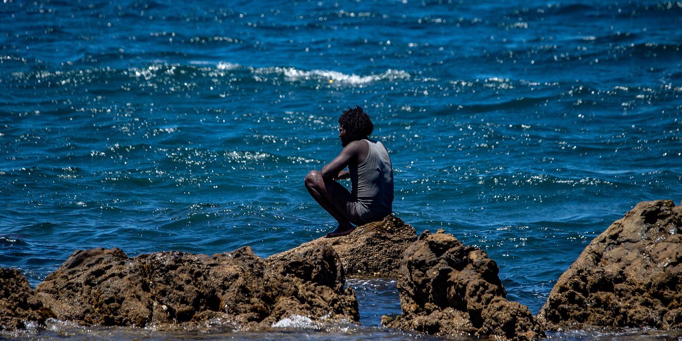 En man som tagit sig från Marocko till Ceuta sitter på stranden på söndagen.