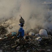 En kvinna går förbi en rykande sophög i Port-au-Prince.