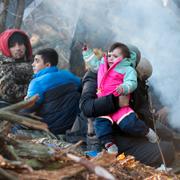 Migranter värmer sig vid en eld.