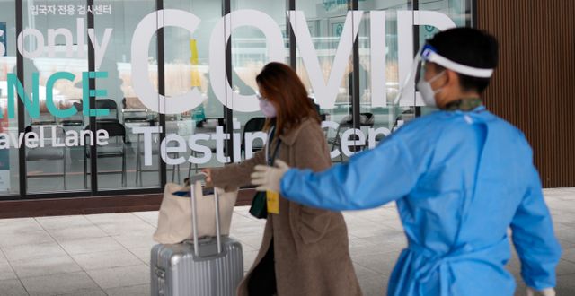 En kvinna som anländer från Kina till Sydkorea passerar en teststation på en flygplats. Lee Jin-man / AP